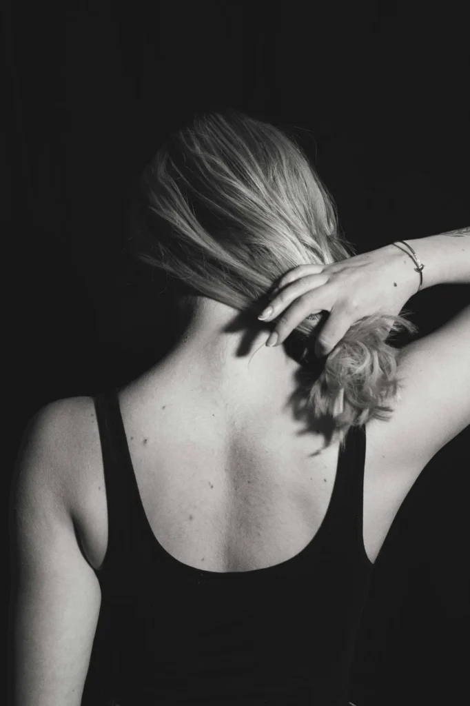 Black and white photo of girl pulling her haor back so you can see here back